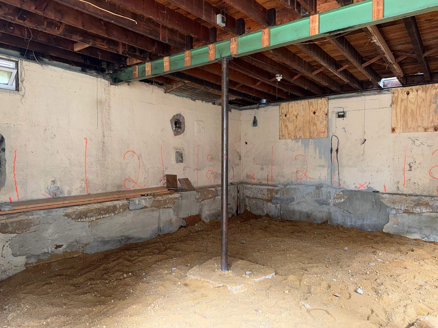 Numbered underpinning walls: Spray painted numbers on the basement walls mark the underpinning sequence, with steel posts carrying the beam above.