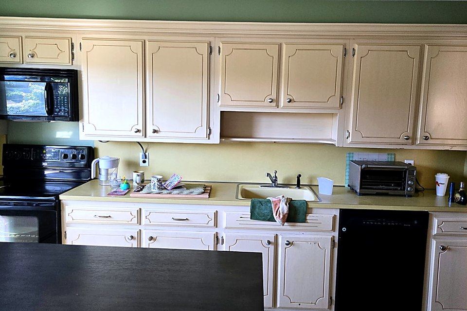 Before the remodel: Cream cabinets, laminate counters, and black appliances.