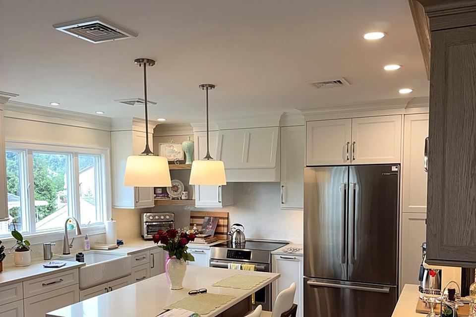 Finished kitchen: White shaker cabinets, pendants over the island, and stainless appliances.