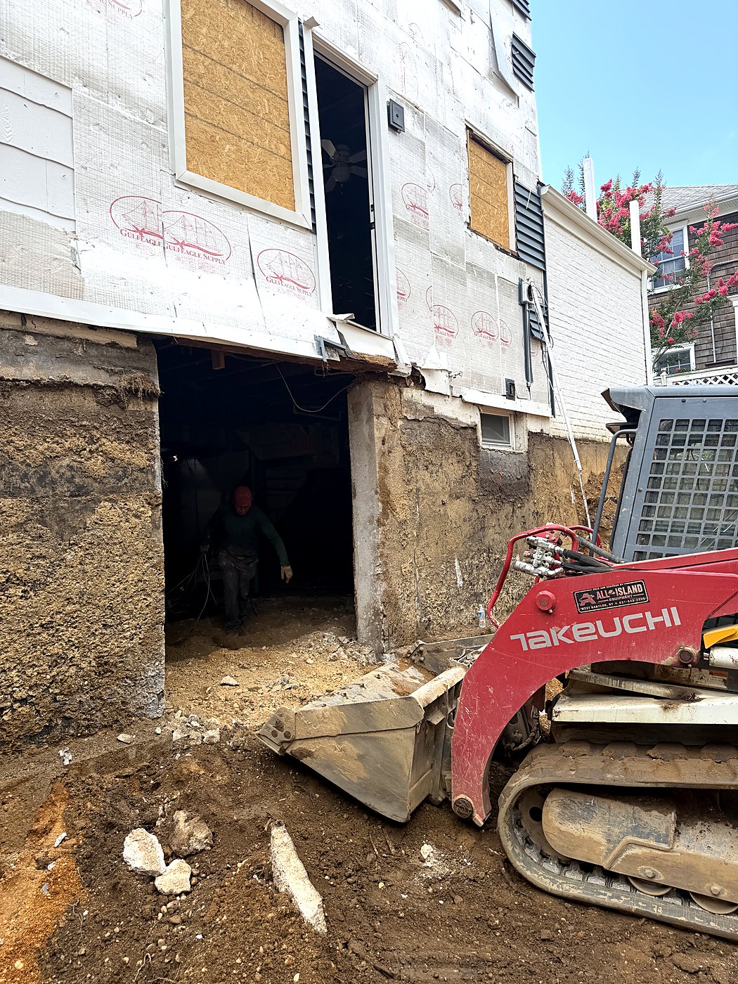 Compact loader moving fill beneath the house during underpinning