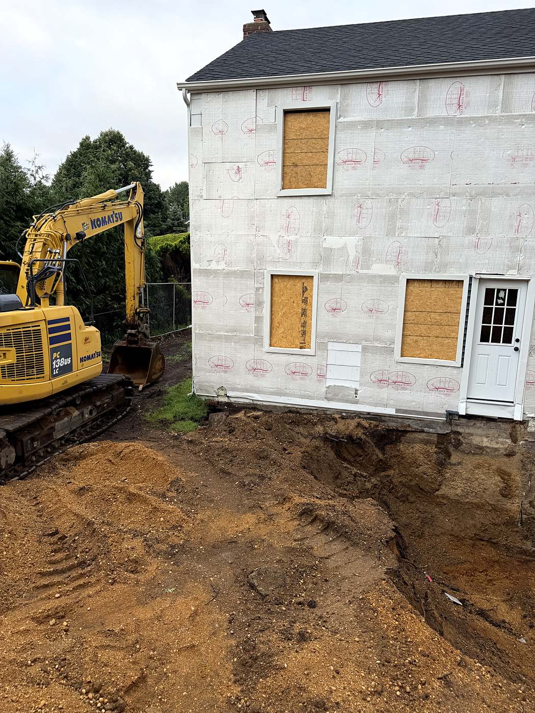 Excavator working alongside the house after the sidewall has been dug out