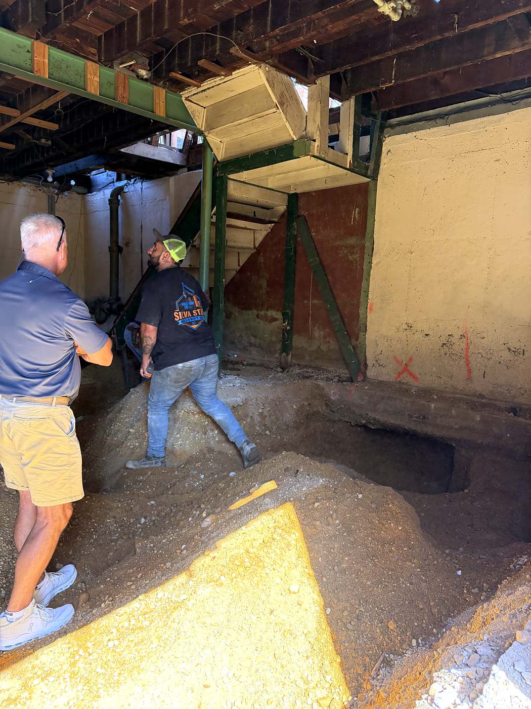 Crew working in the basement below the new steel beam and temporary shoring