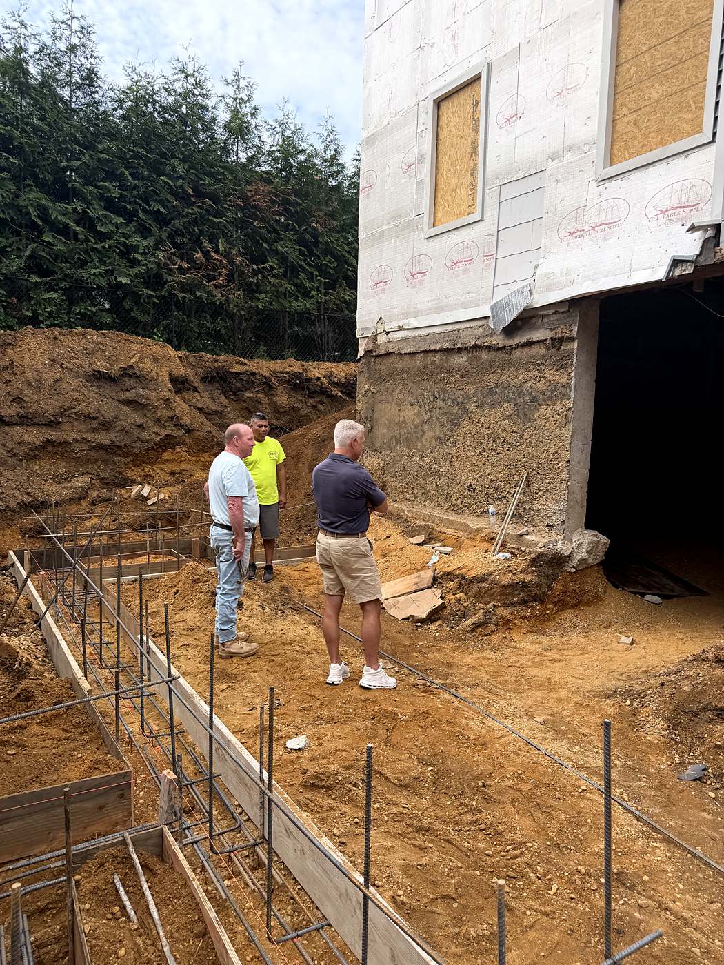 Crew walking the rebar and footing forms laid out beside the house