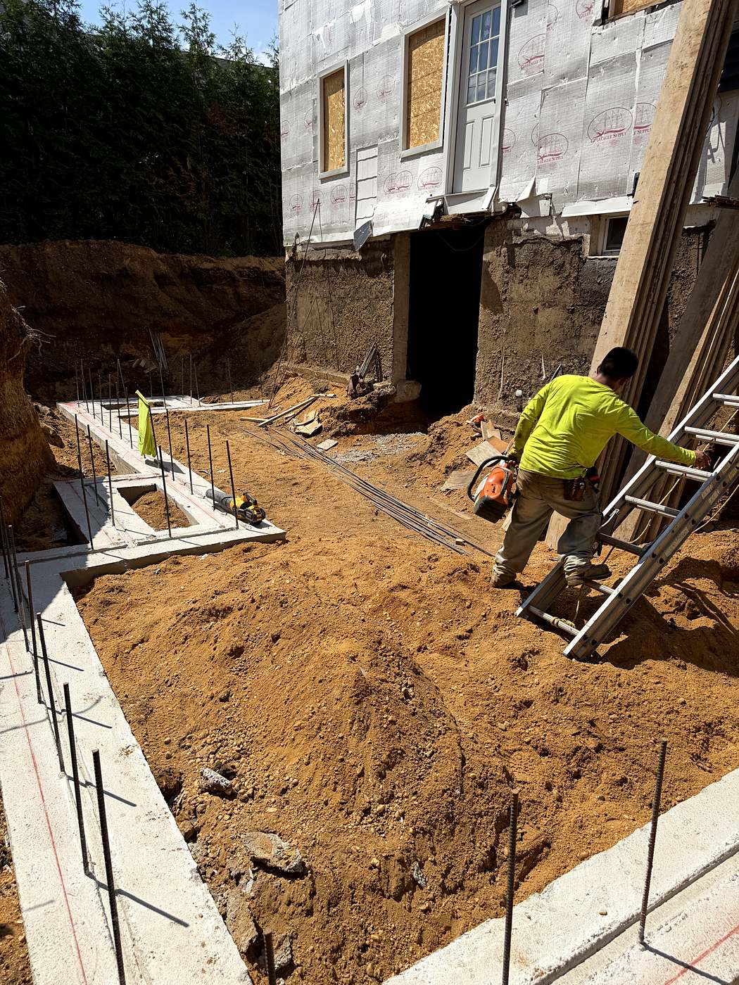 Crew member setting rebar in the footing forms before the foundation pour