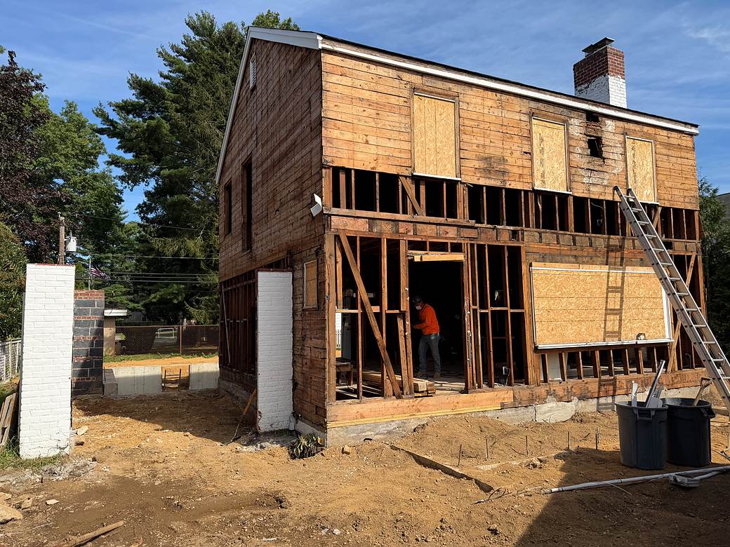 Two-story home opened to the studs with new framing across the rear wall and a new foundation alongside