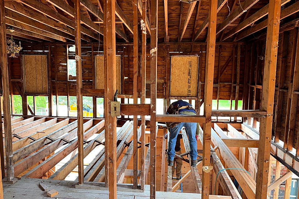 Crew member framing inside the addition among the new studs and joists
