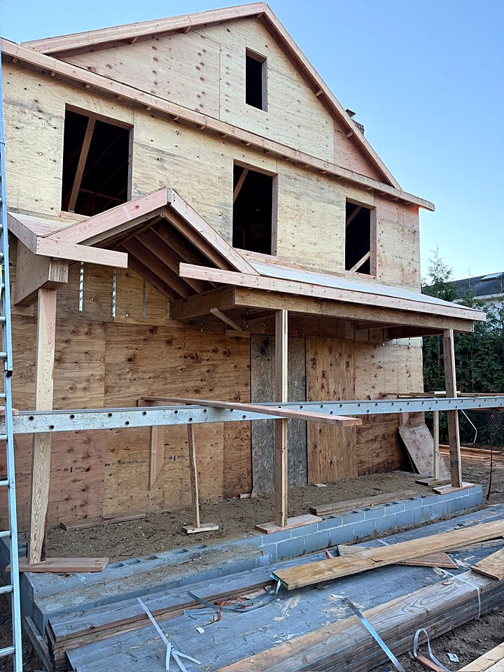 Front of the house with the new second story framed and sheathed and the gables in place