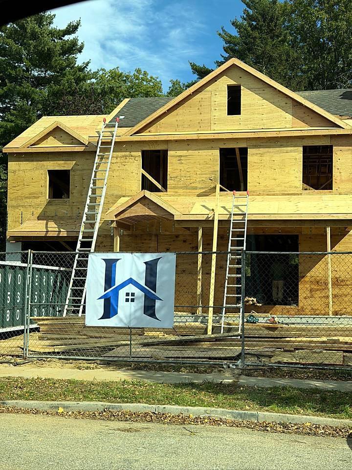 The sheathed front of the house with ladders up and a HomeCore sign on the lawn