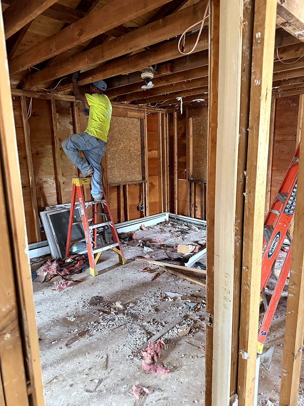 Crew member on a ladder during demolition of the bedroom and bath
