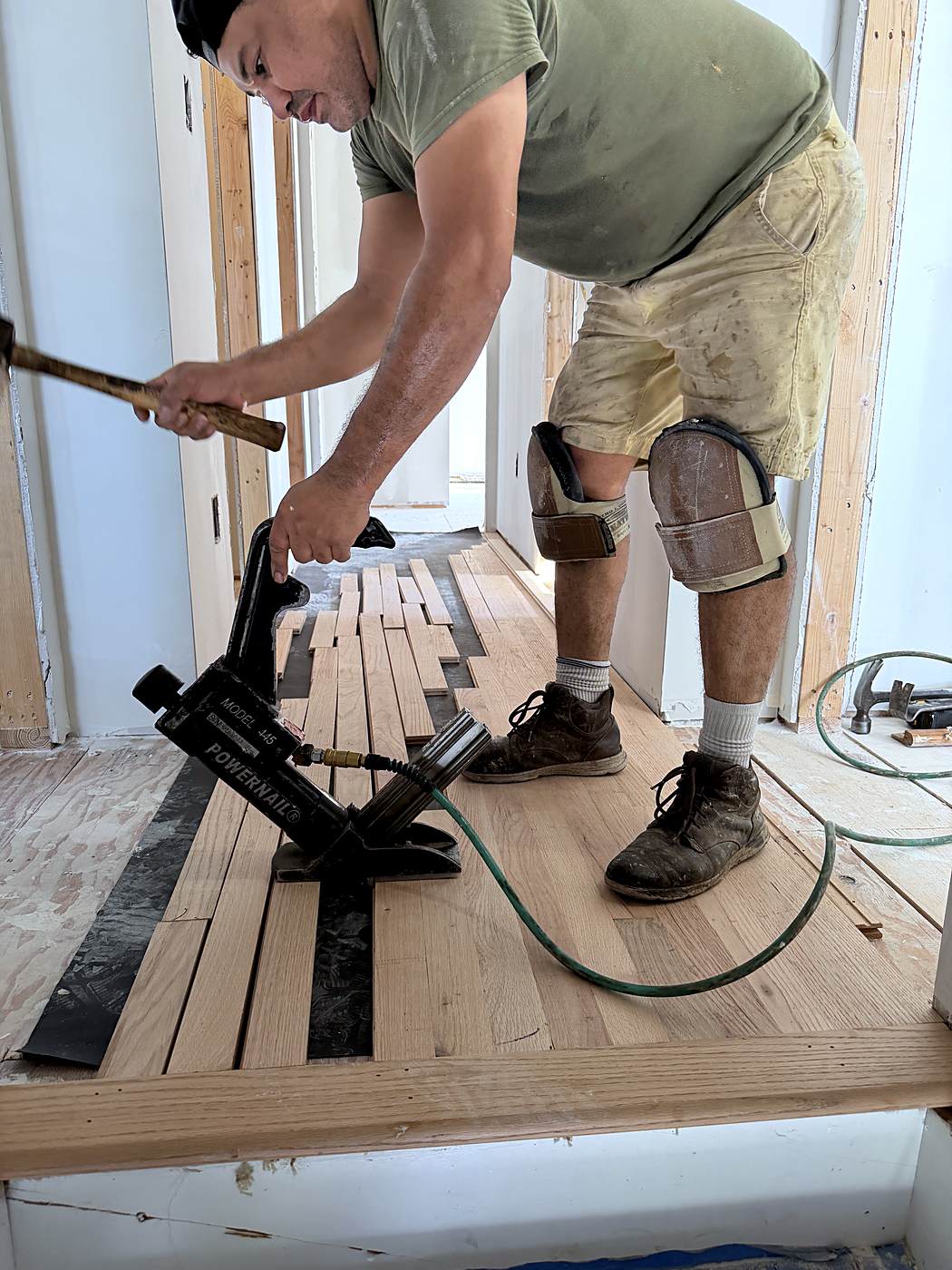 Crew member nailing down new hardwood flooring with a floor nailer