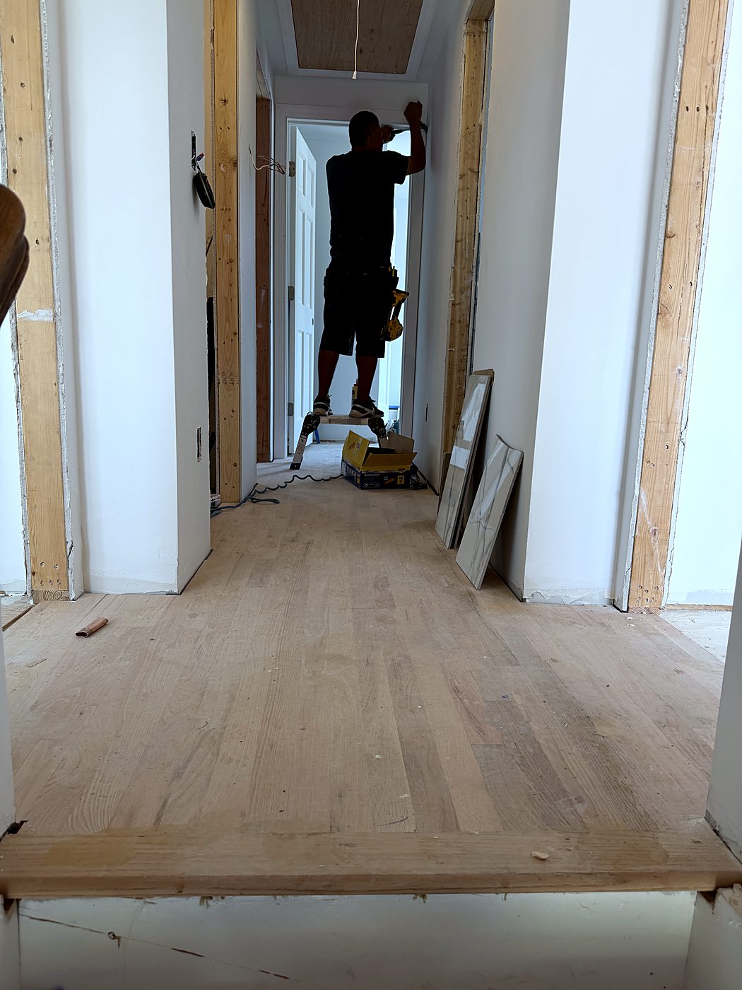 Crew member sanding the new hardwood floor in the finished hallway