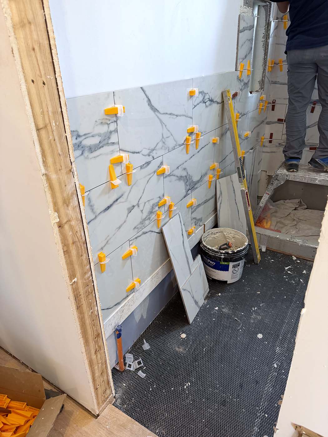 Large-format marble tile going up on the bathroom wall during installation