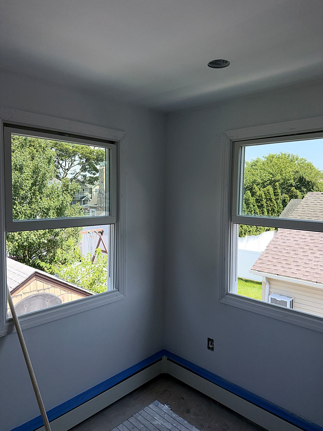 Finished bedroom painted soft gray with two new windows and the trim taped off