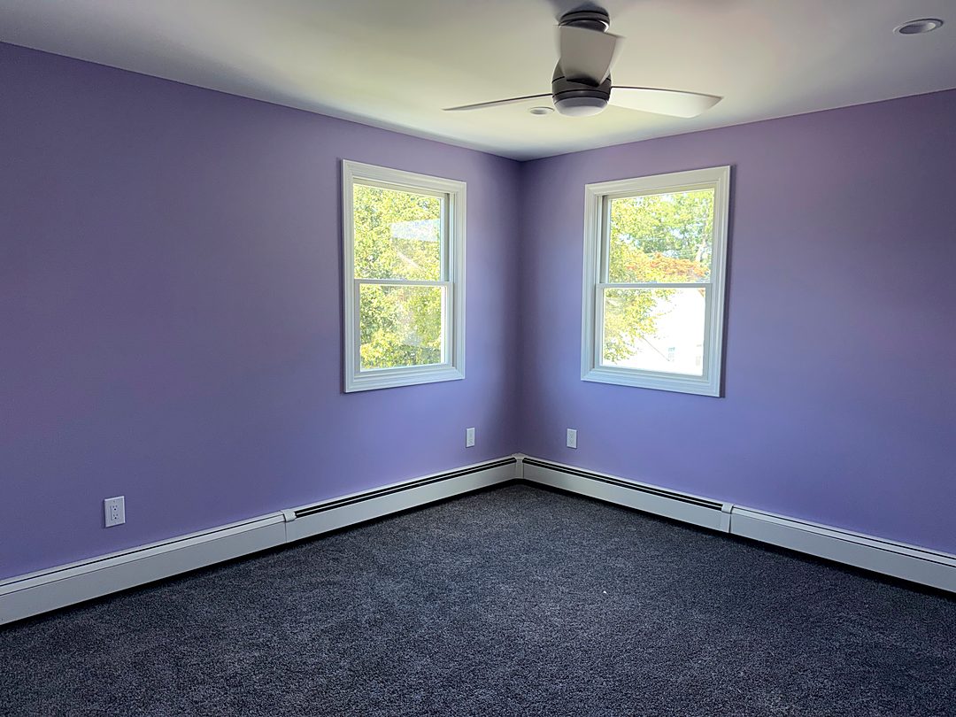 Finished bedroom with lavender walls, new windows, and new carpet