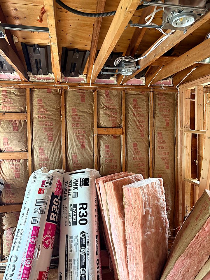 Rolls of insulation and lumber staged in the framed room