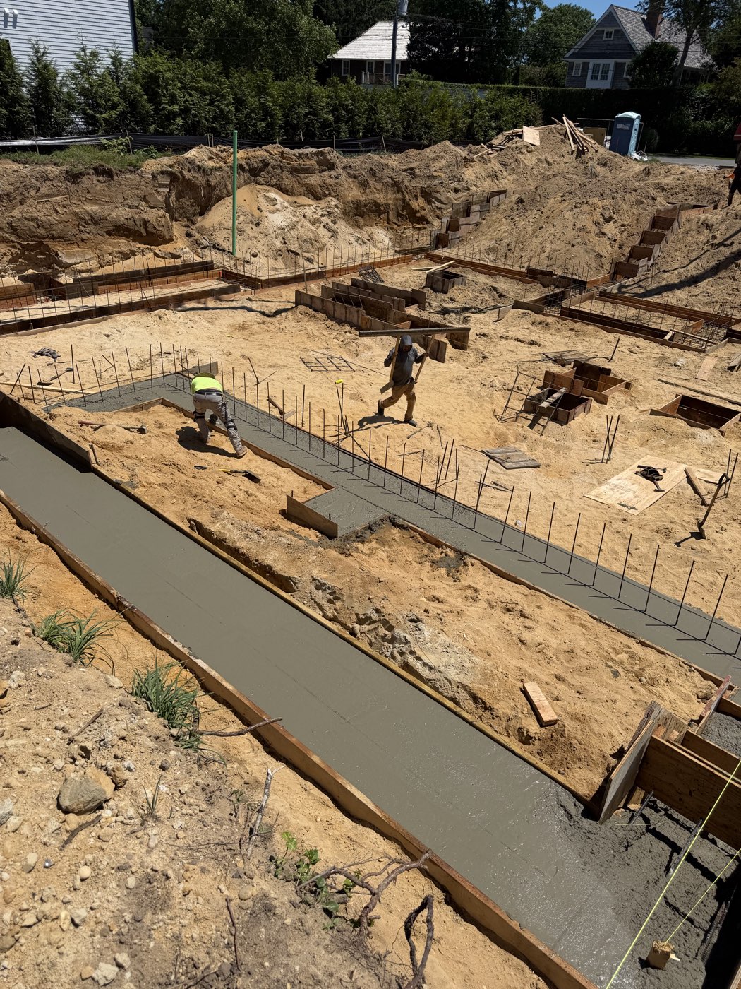 Freshly poured footing running the length of the excavation with rebar dowels set