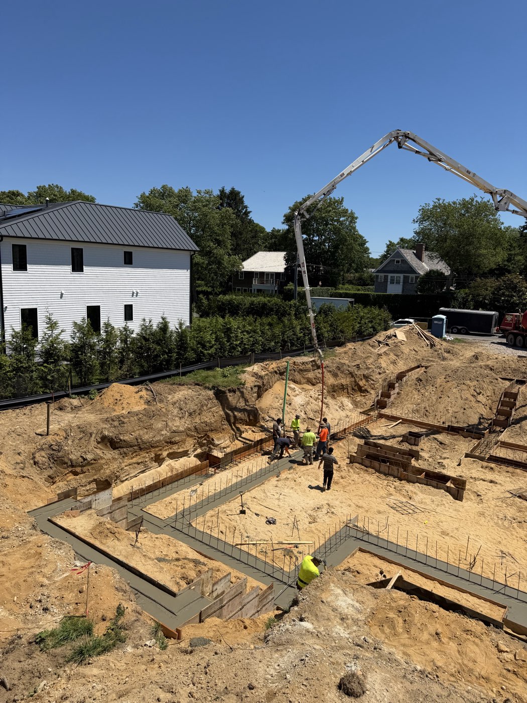 Crew placing concrete in the foundation forms as the footprint of the house takes shape