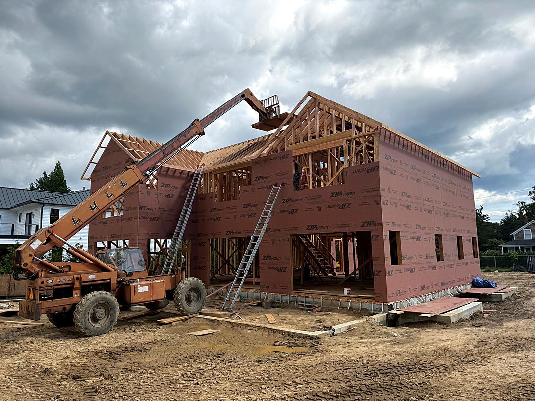 Telehandler lifting materials to the roof of a sheathed two-story custom home