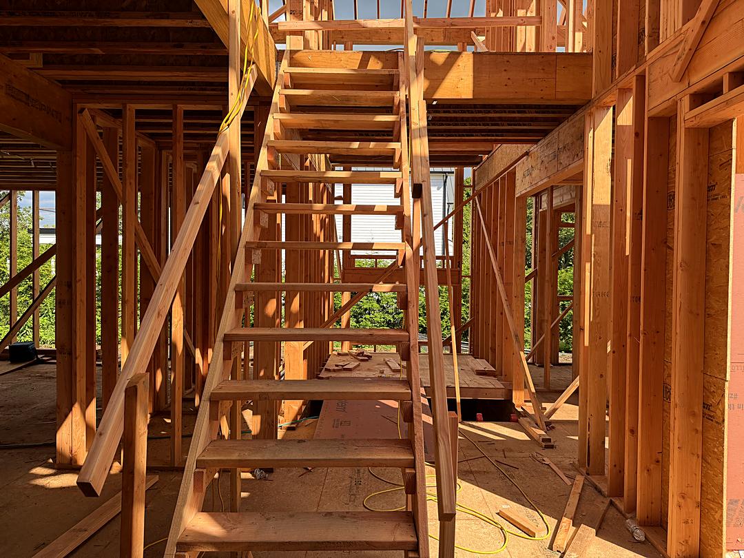 Rough stair framing inside a custom home, surrounded by new wall studs