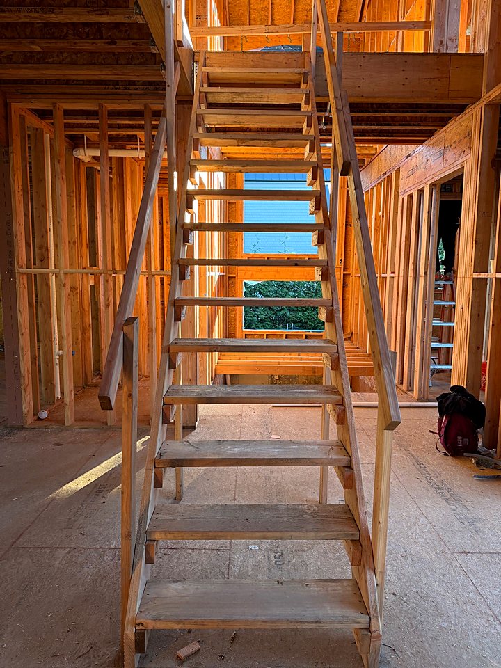 Temporary stairs set between floors inside the framed custom home