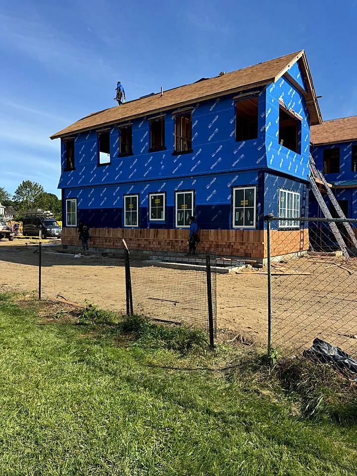 Rear of the custom home in house wrap with the roof on