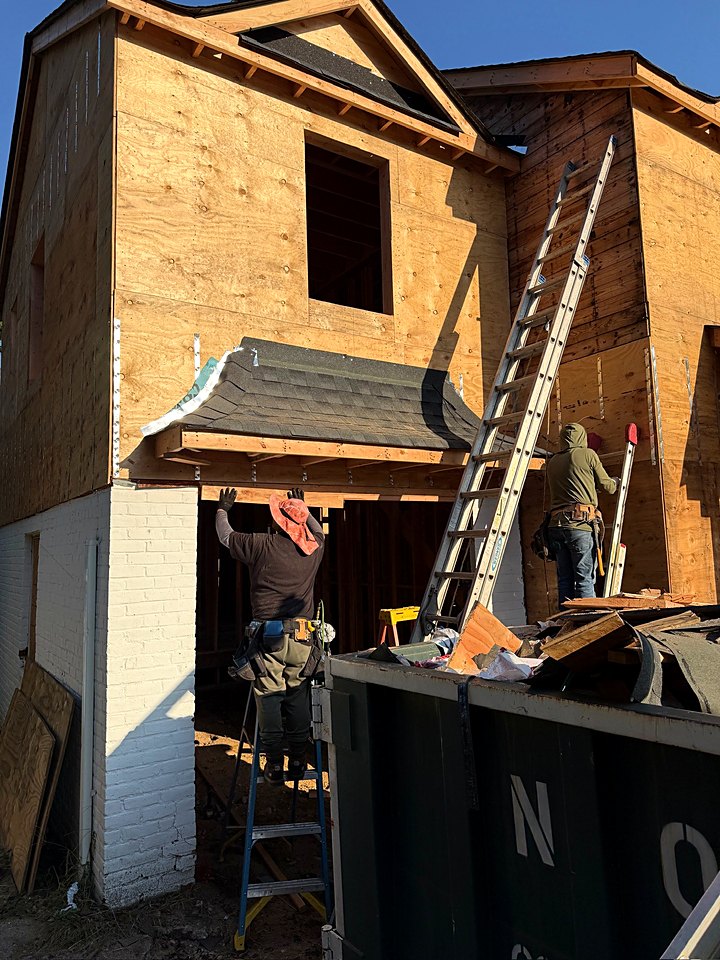 Crew on ladders installing sheathing and a roof overhang on the custom home