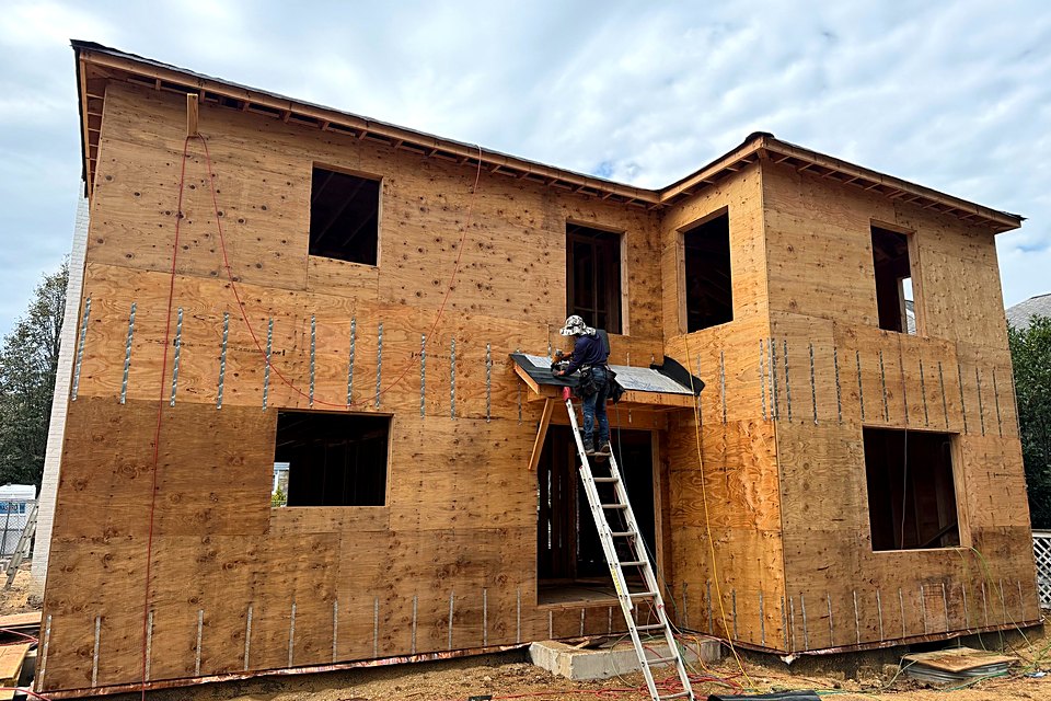 Crew member on a ladder installing underlayment on the entry roof