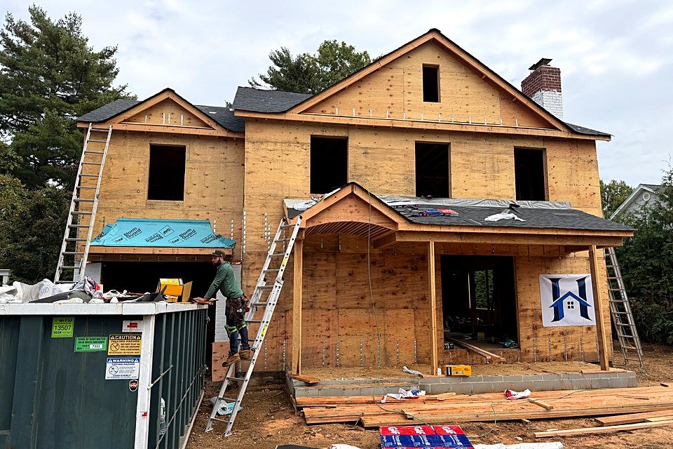 Sheathed custom home with the HomeCore Construction sign and shingles staged out front