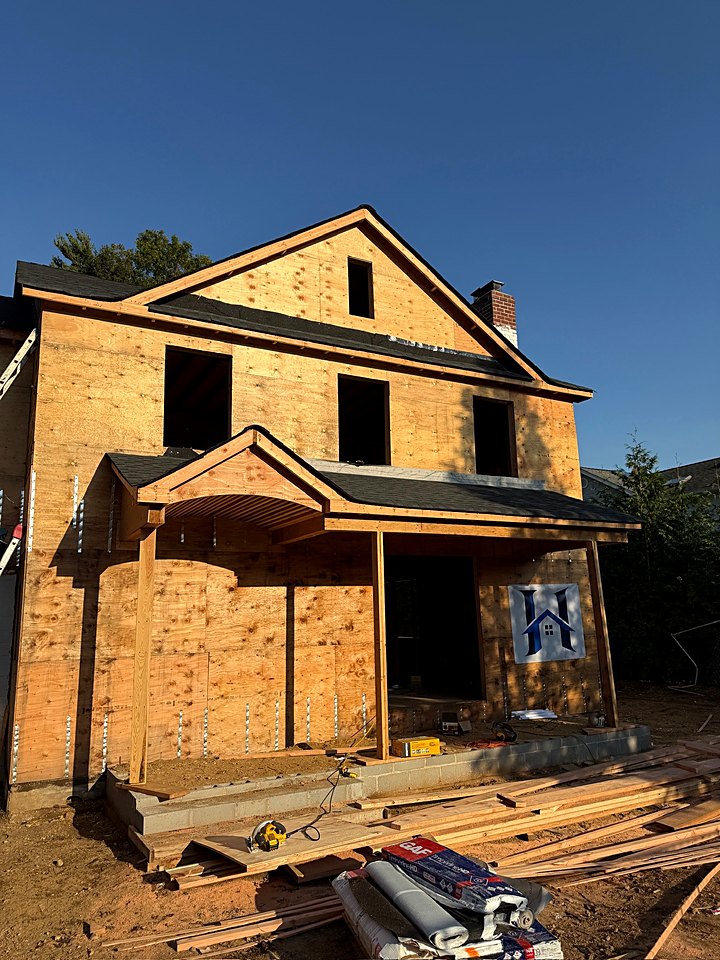 Framed front porch and HomeCore Construction banner on the sheathed custom home