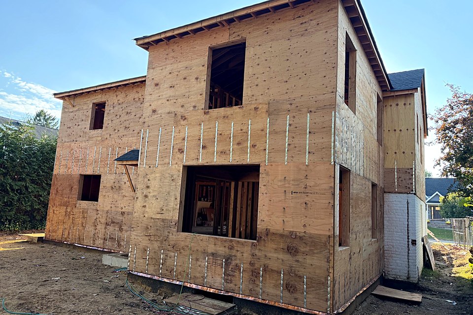 Wide view of the custom home fully sheathed with window openings cut