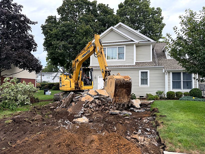 Excavator breaking apart the old concrete slab