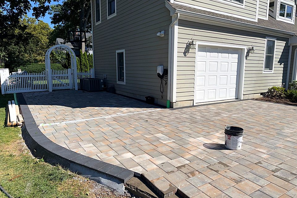 New paver driveway with a curved charcoal border along the lawn