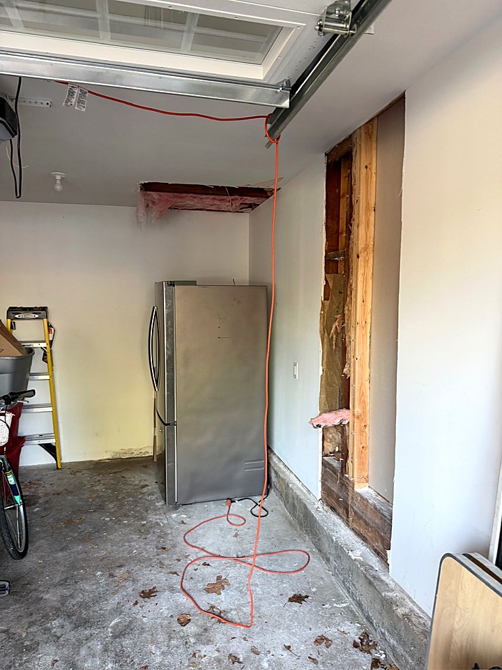 Garage wall opened to the studs with insulation exposed for a new pass-through