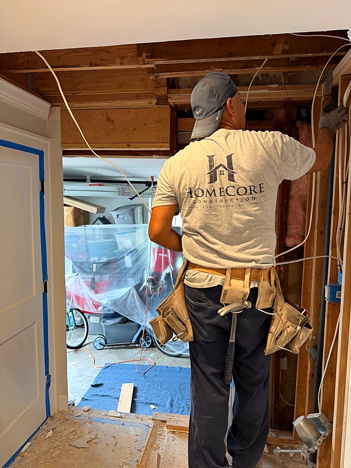 Crew member in a HomeCore shirt working the new opening between the house and garage