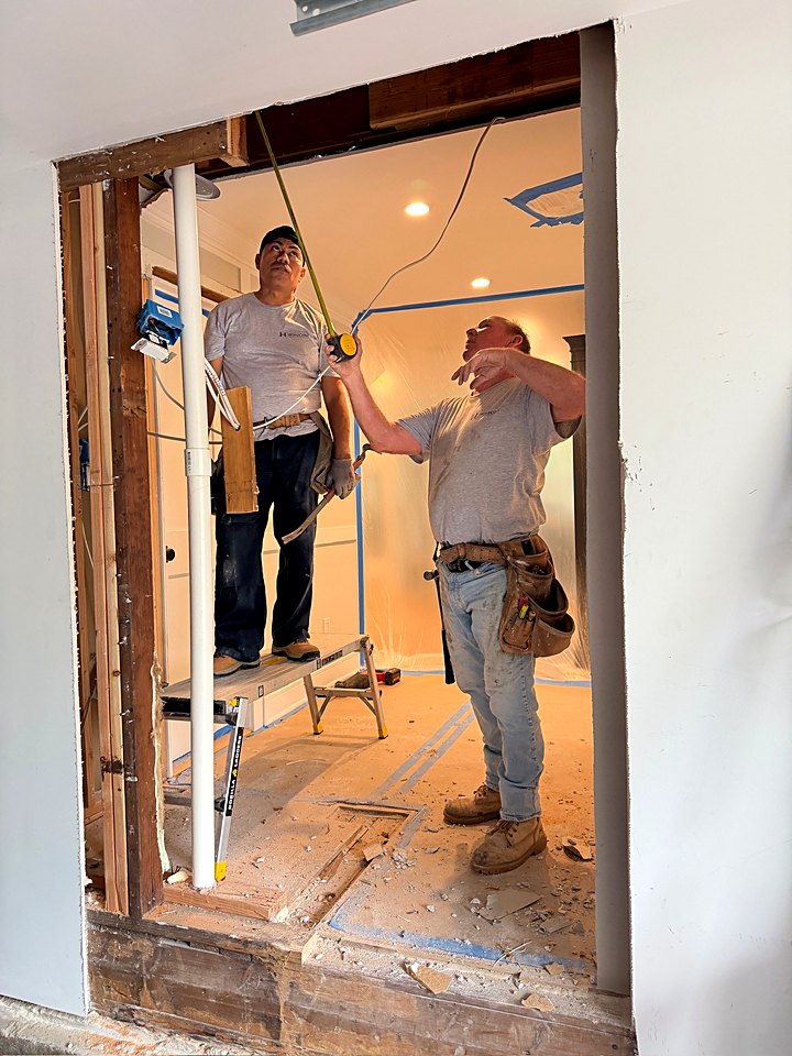 Two crew members measuring and framing the new garage opening