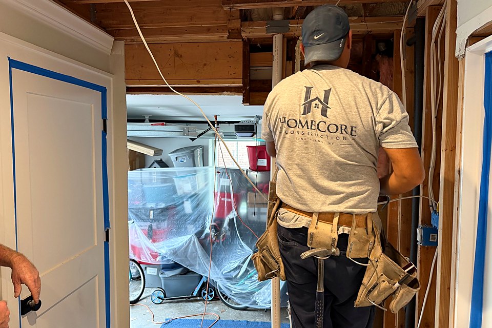 Crew member at the opened wall looking through into the garage during pass-through framing