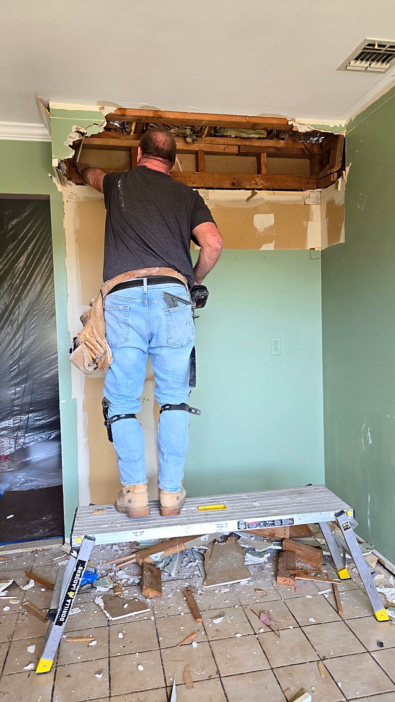 Crew member removing a bulkhead soffit above the kitchen
