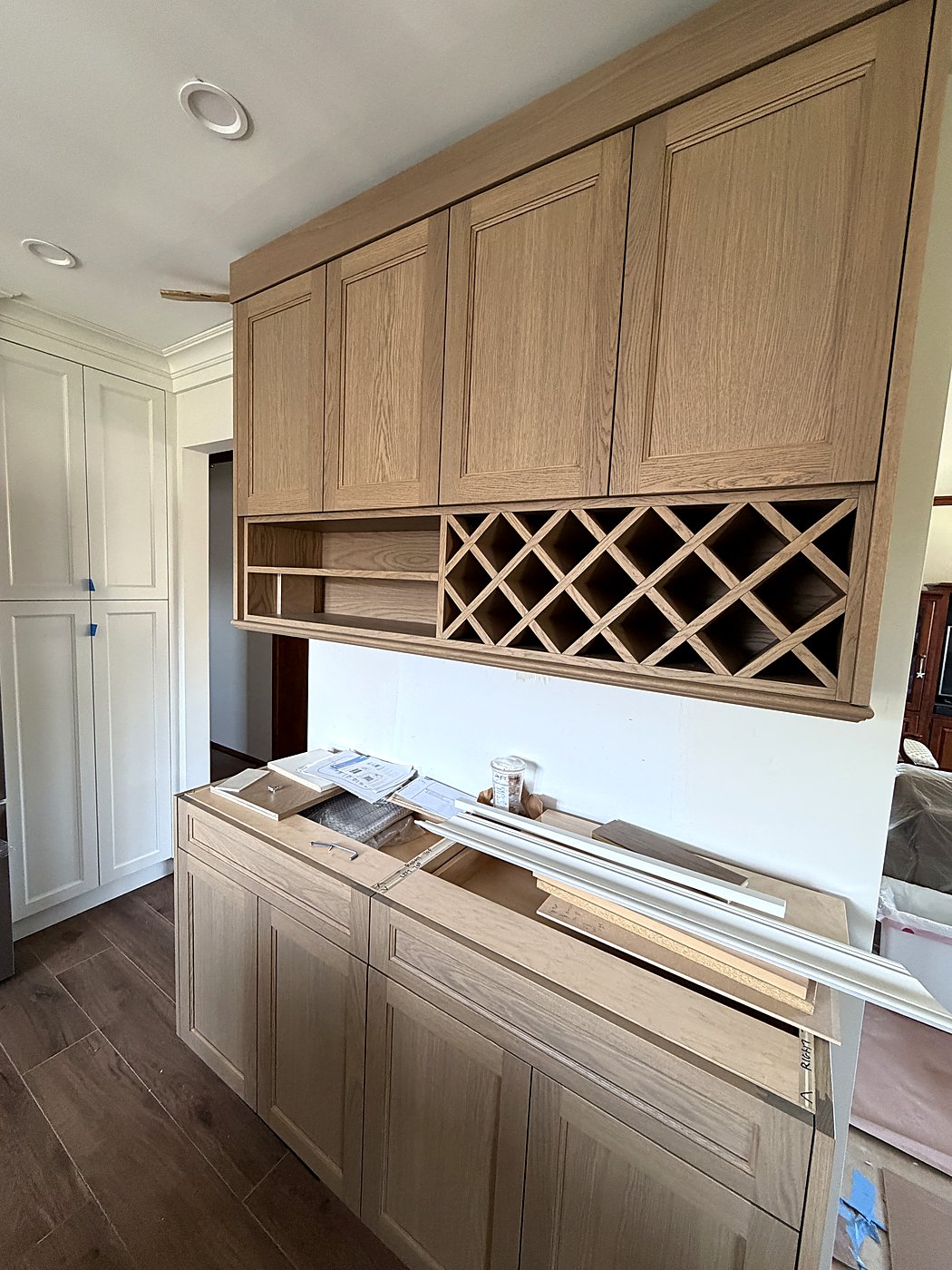 Near-finished kitchen with two-tone cabinets and a built-in wine rack