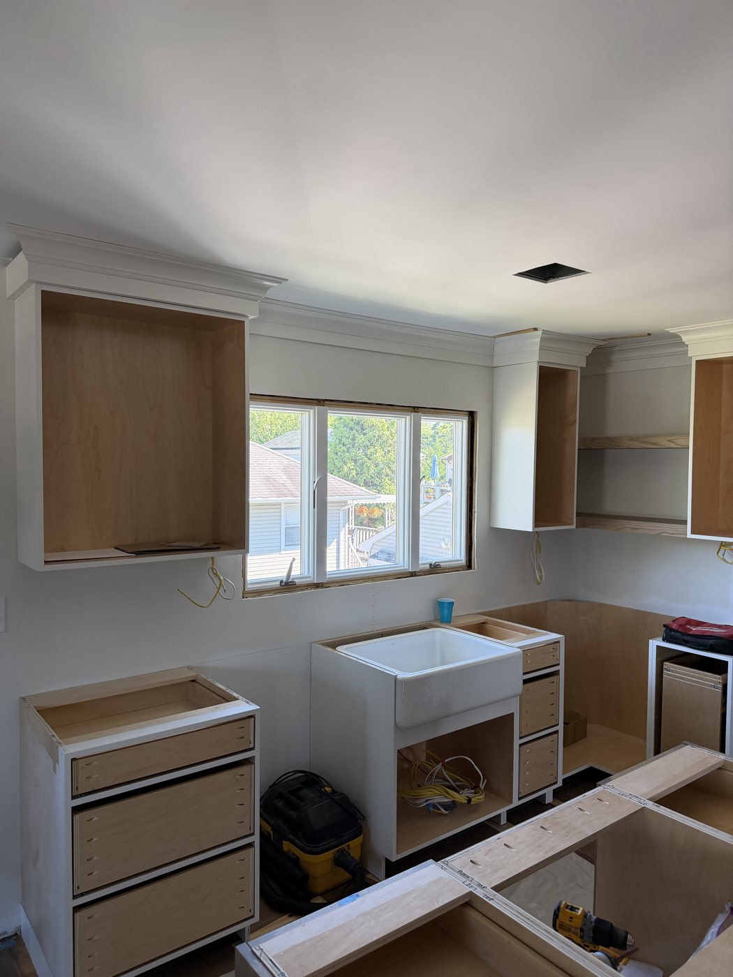 White cabinet boxes and a farmhouse apron sink set beneath the new kitchen window