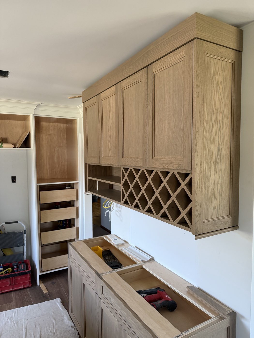 White oak upper cabinets with a diamond lattice wine rack and pull-out pantry shelving