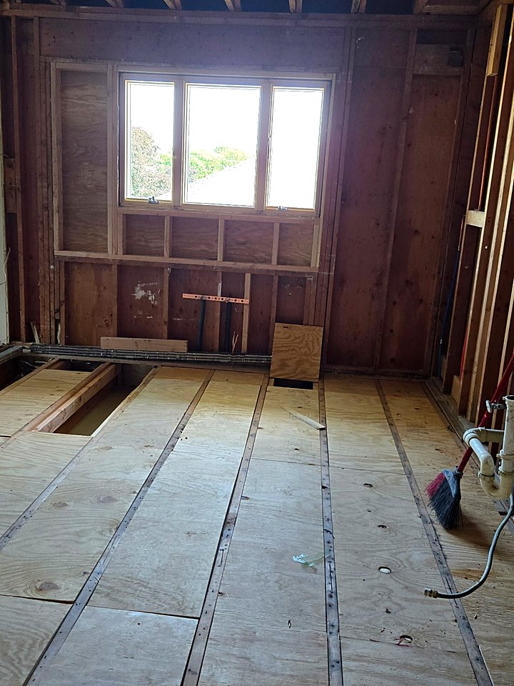 Kitchen gutted to the studs and subfloor with the new window opening framed