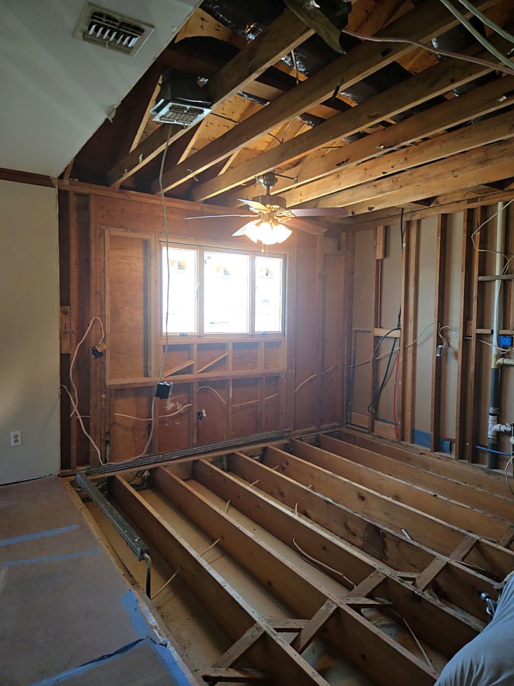 Kitchen floor opened down to the joists with the ceiling framing exposed above