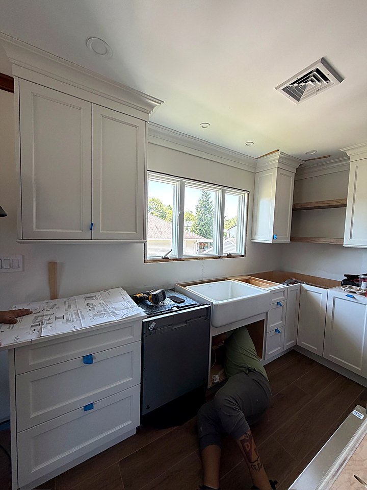 Installer hooking up the dishwasher beside the new farmhouse sink