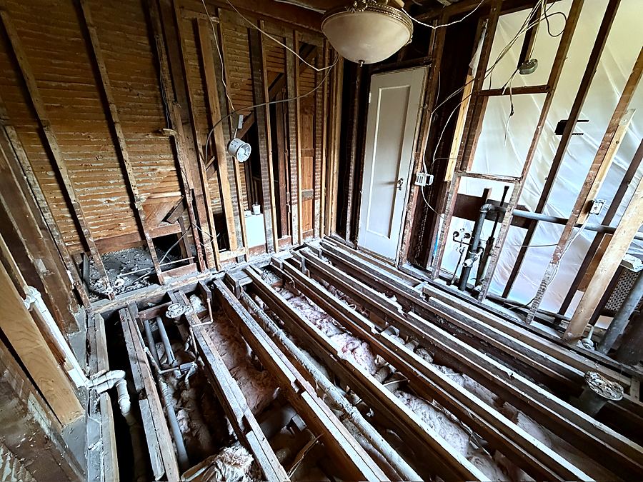 New plumbing runs set between the opened floor joists