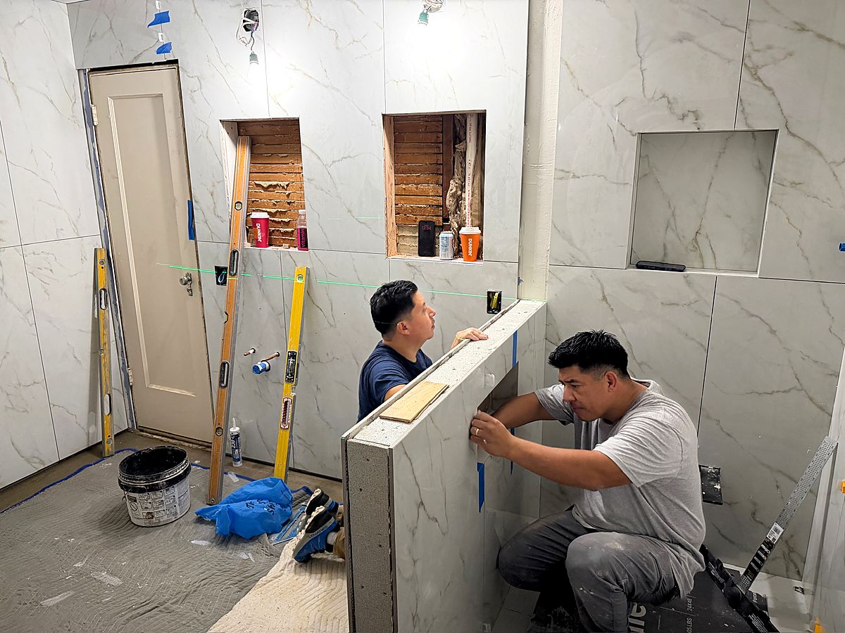 Crew members setting large format tile on the bathroom wall