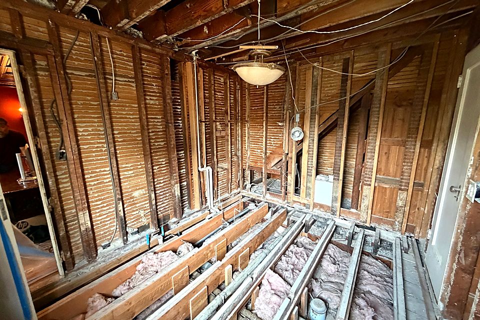 Wide view of the opened floor joists with new plumbing and wiring runs