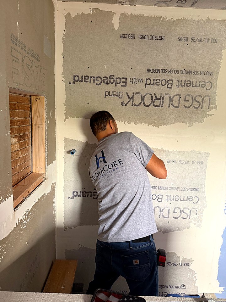 Crew member fastening cement board on the shower wall
