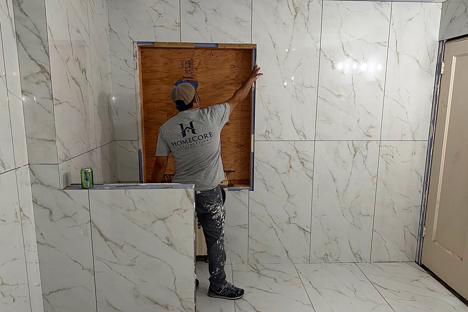 Crew member working at the window opening in the newly tiled bath