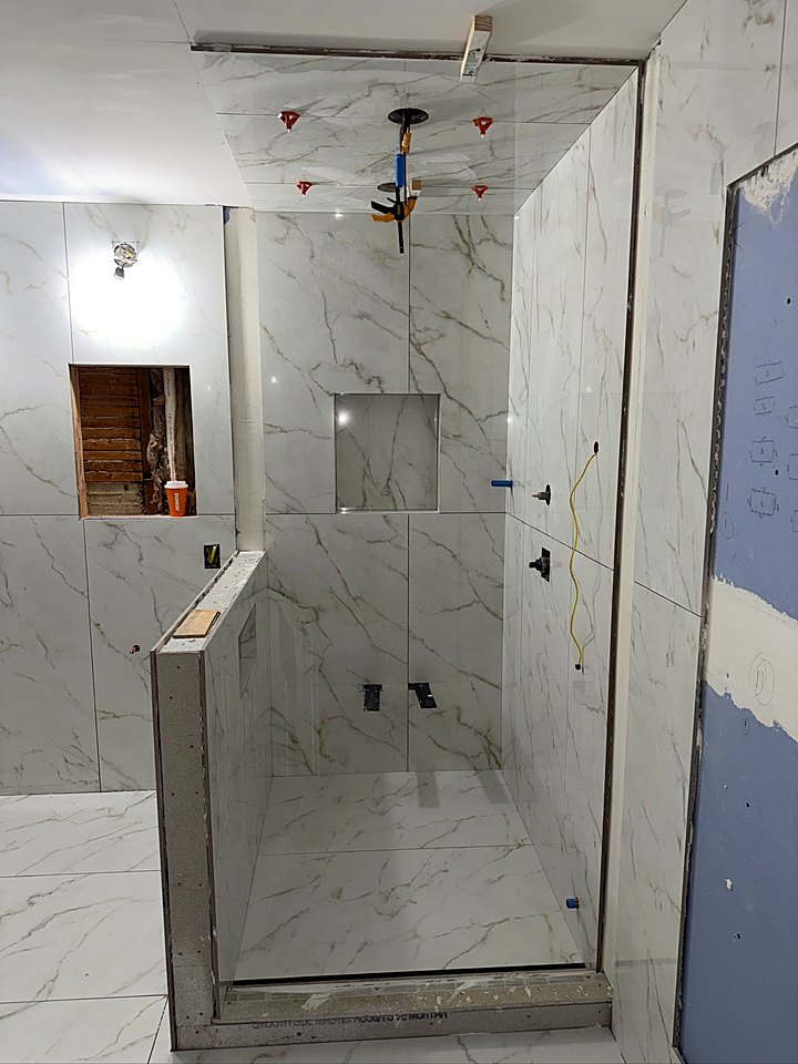 Walk-in shower with a glass panel, rain head, and marble-look tile