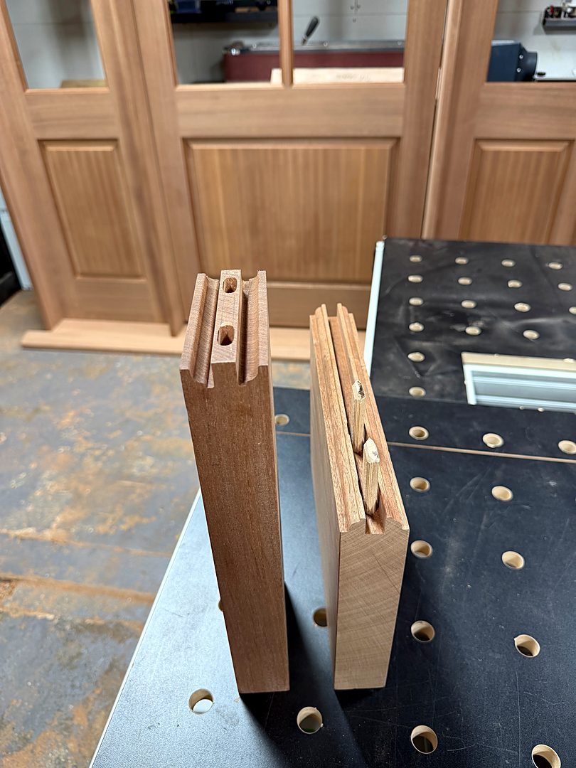 Door rails and stiles with machined joinery standing on a shop workbench